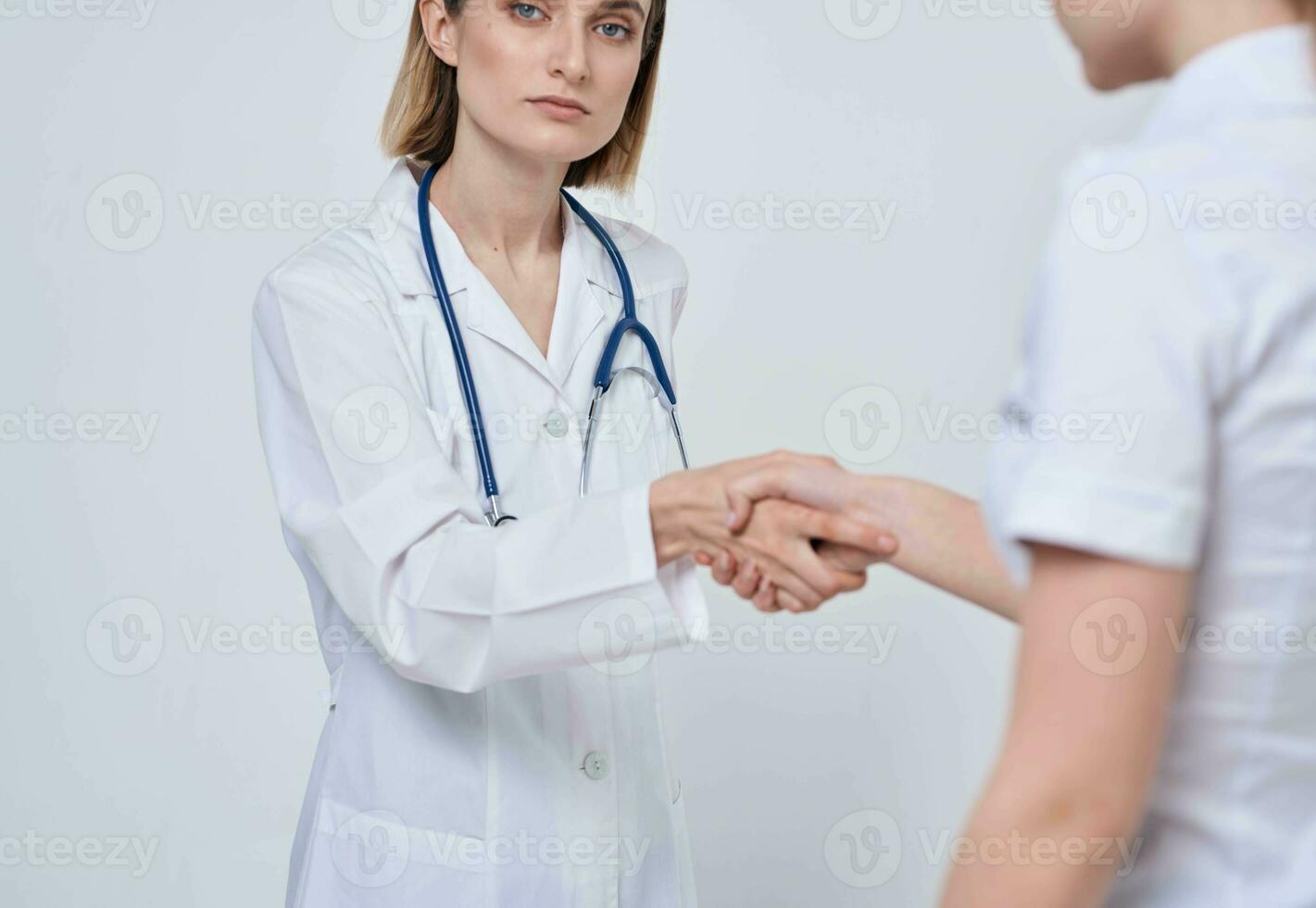 Professional doctor woman shakes hand of a female patient on a light background photo