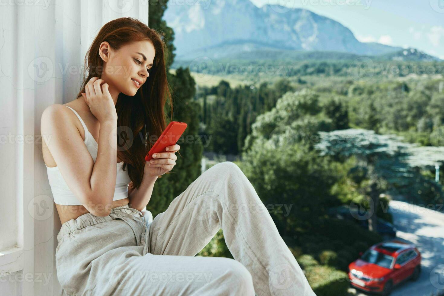 cheerful woman with long hair on an open balcony Green nature summer day unaltered photo