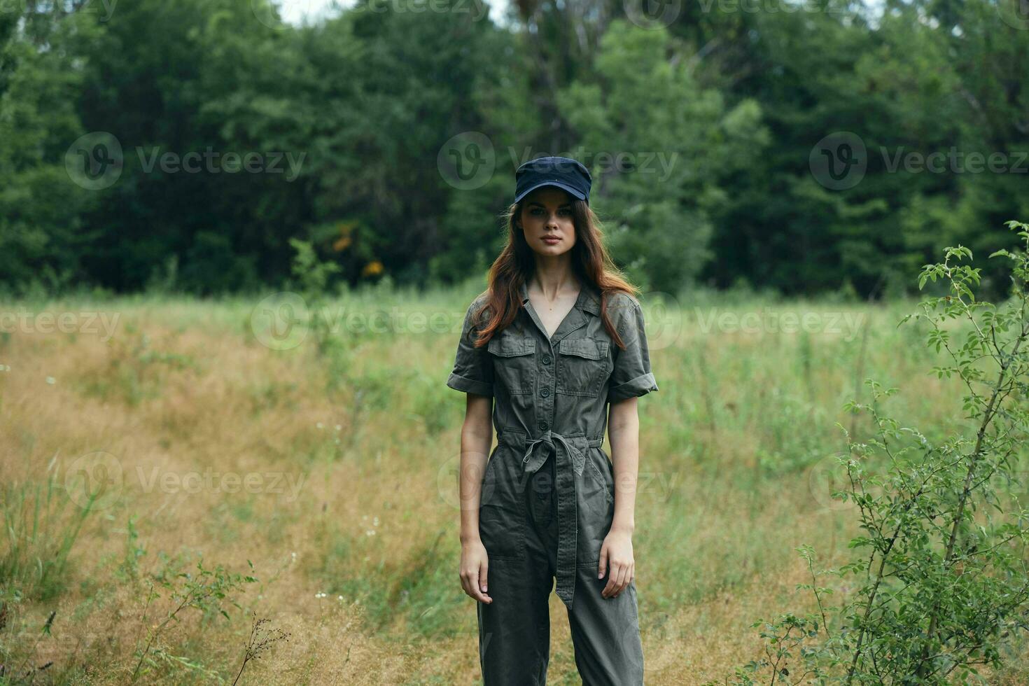 woman in nature in a gray overalls and a cap on her head photo