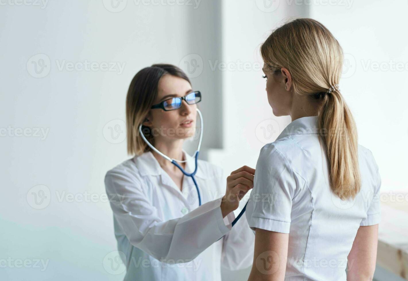 Woman doctor with stethoscope and glasses examines the patient health model photo