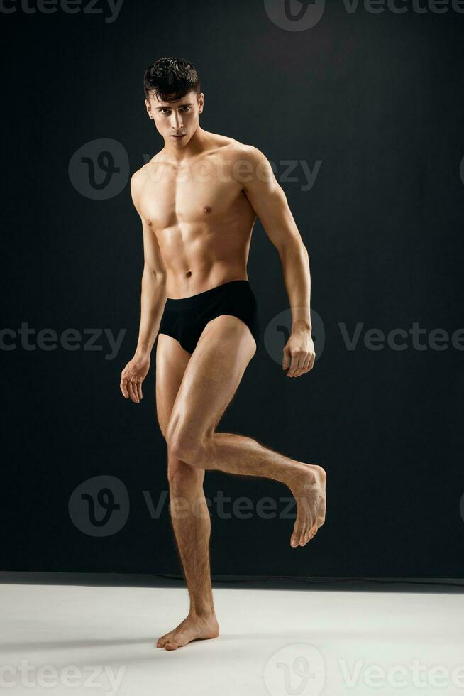 sporty man in black shorts with a pumped body on a dark background model photo