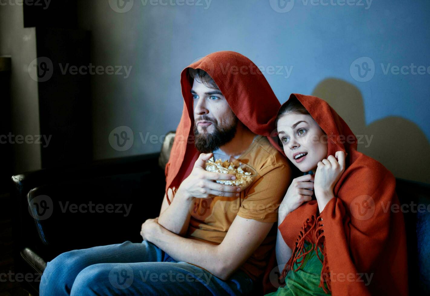 un hombre y un mujer con un rojo tartán en su cabezas son sentado en el sofá en frente de el televisión adentro foto