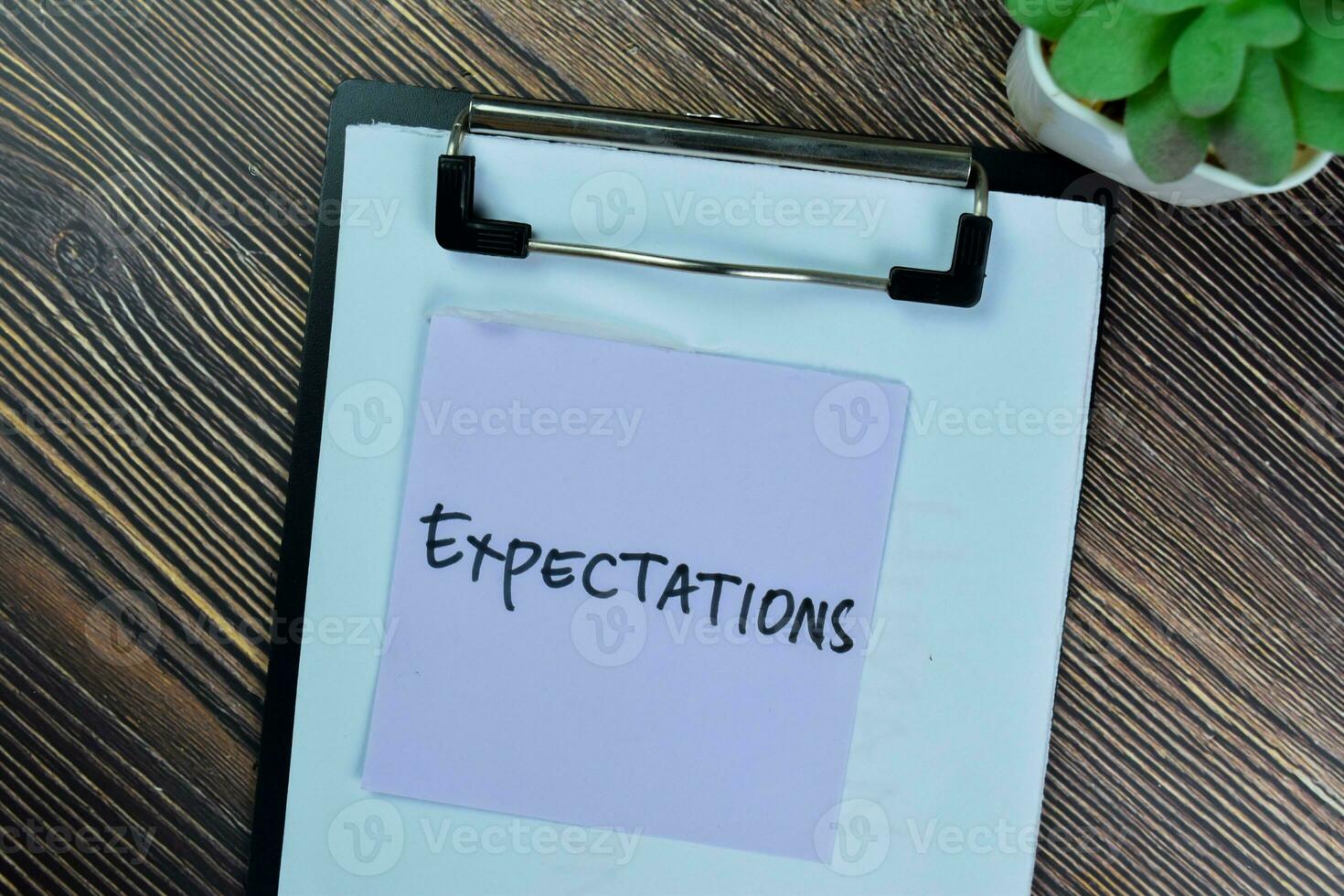 Concept of Expectations write on sticky notes isolated on Wooden Table. photo