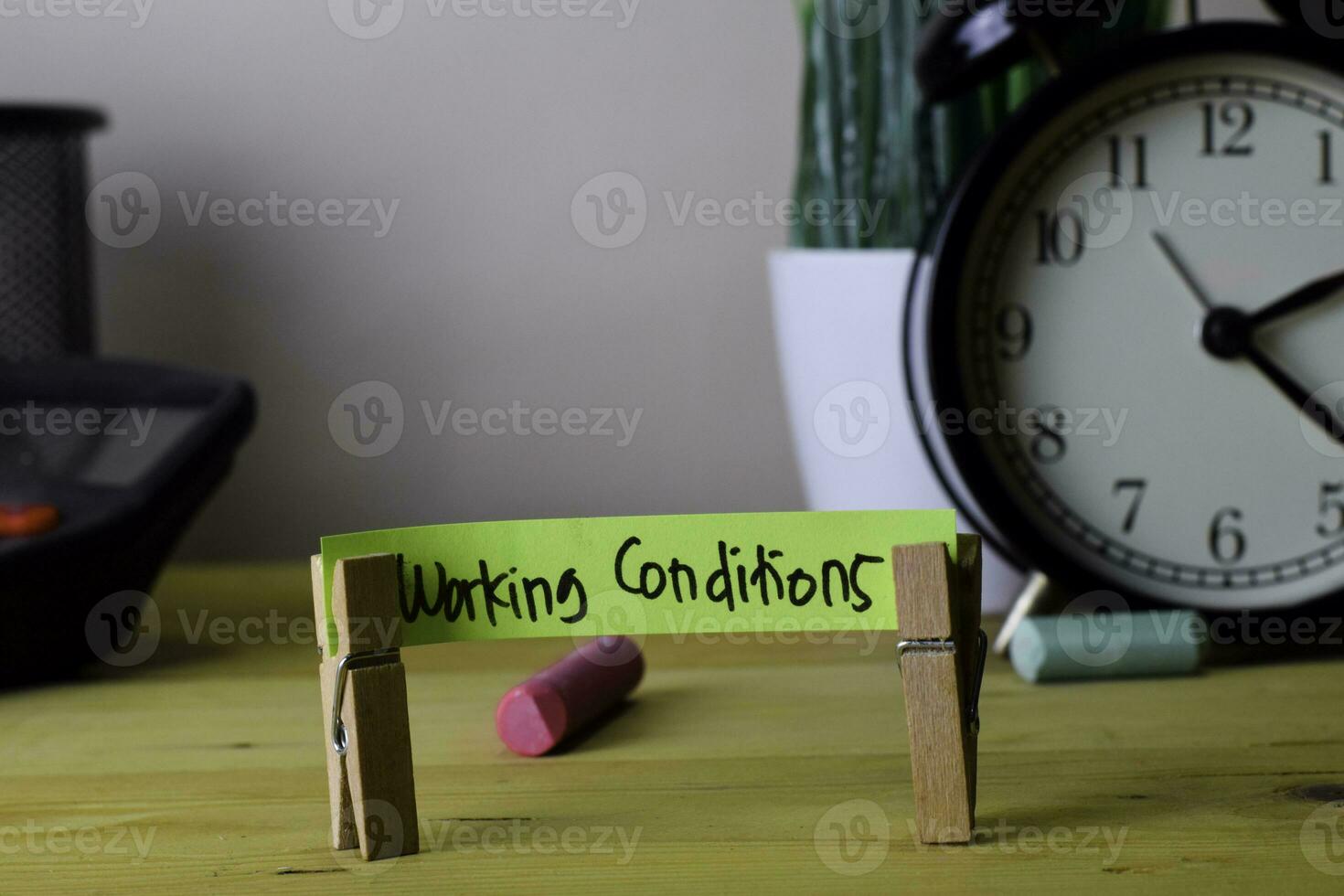 Working Conditions. Handwriting on sticky notes in clothes pegs on wooden office desk photo