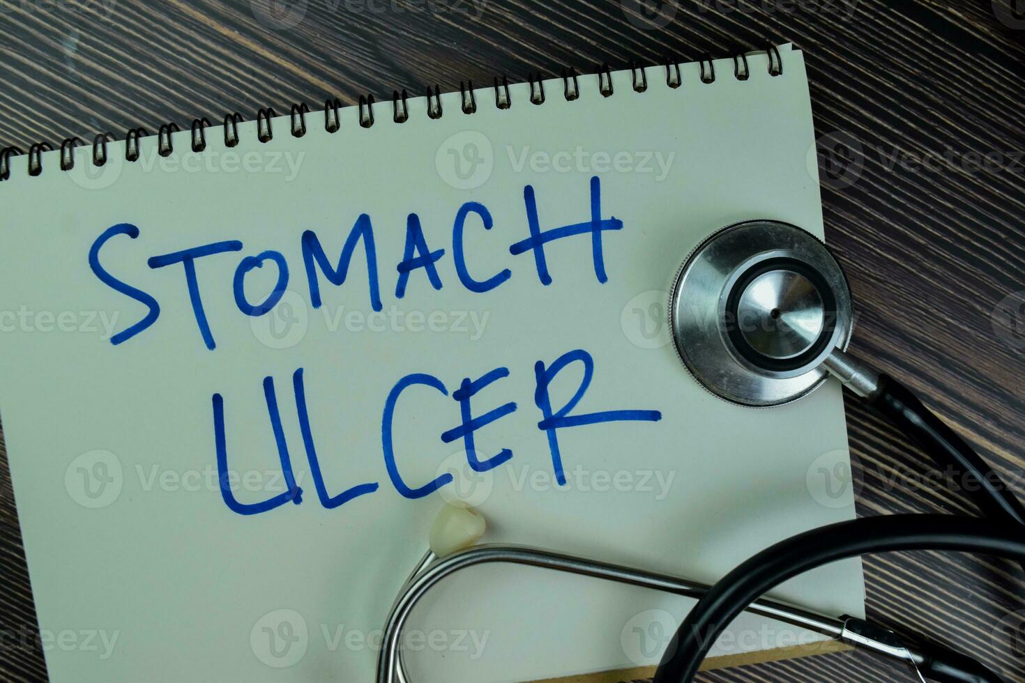 Concept of Stomach Ulcer write on a book isolated on Wooden Table. photo