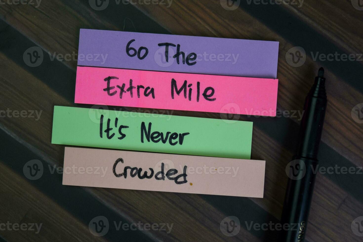 Go The Extra Mile It is Never Crowded write on sticky notes isolated on Wooden Table. photo