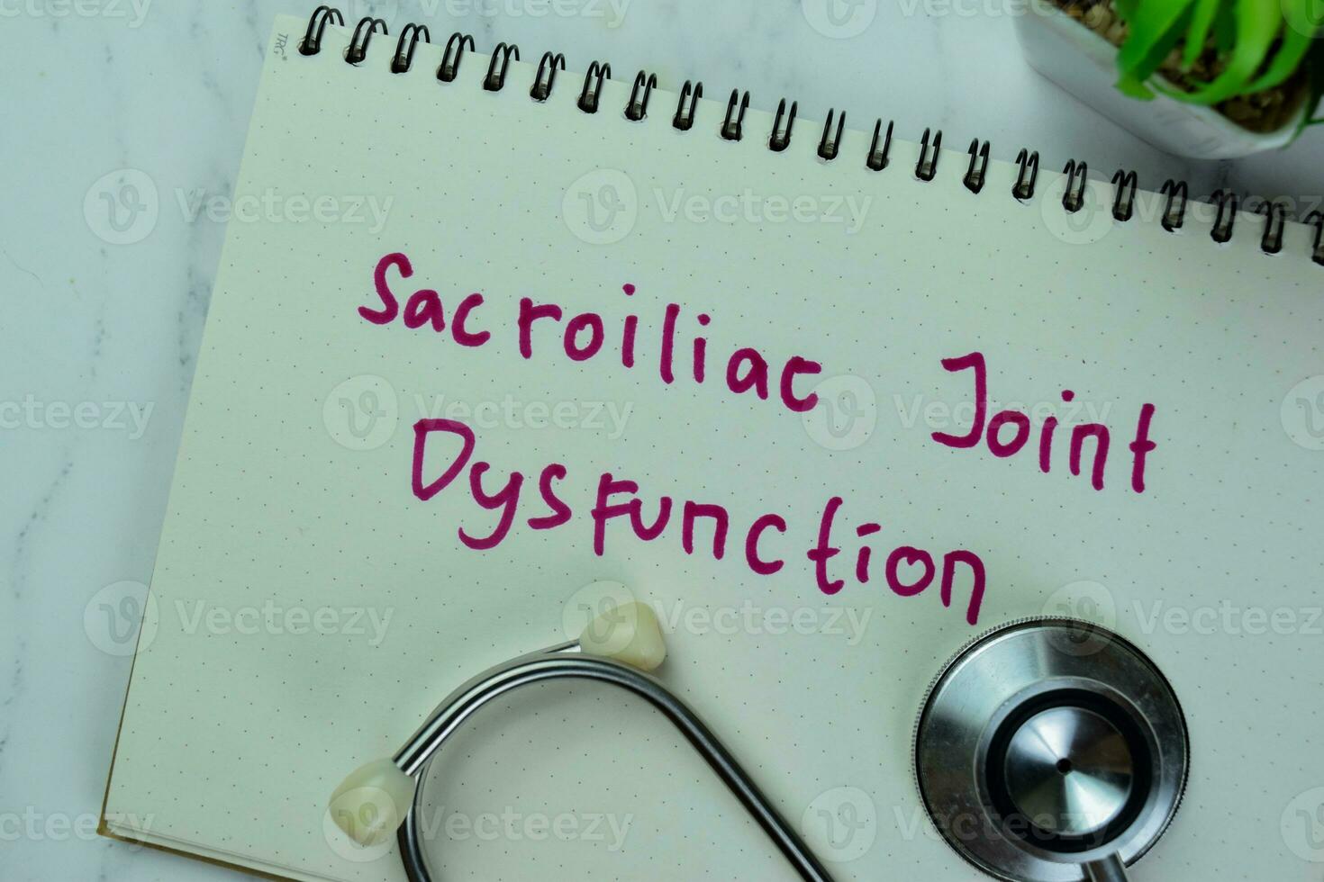 Concept of Sacroiliac Joint Dysfunction write on a book isolated on Wooden Table. photo