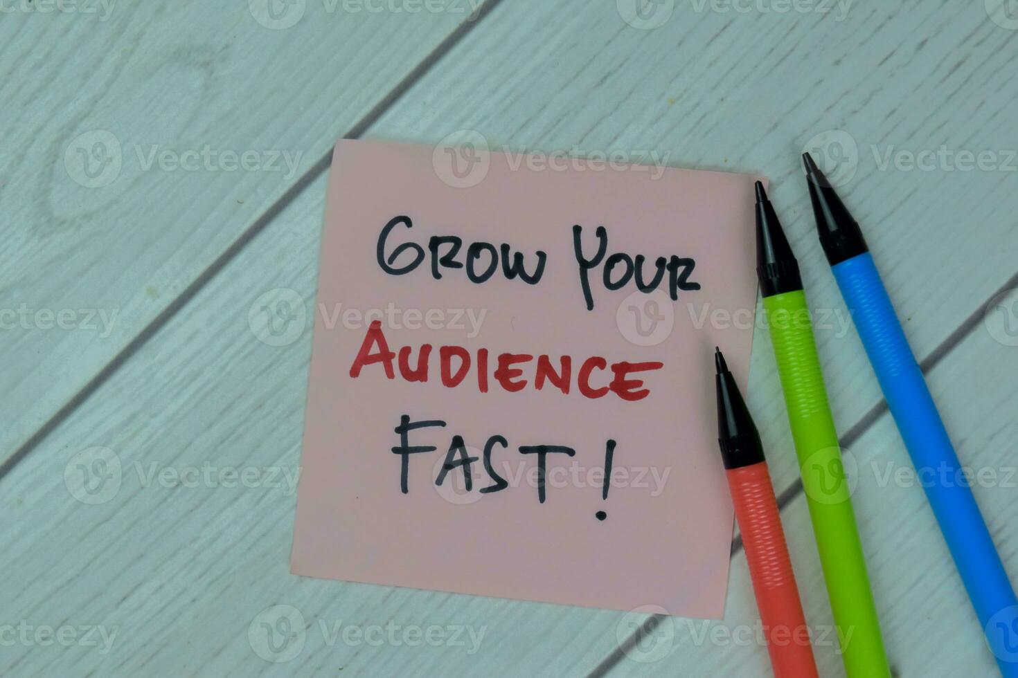 Concept of Grow Your Audience Fast write on sticky notes isolated on Wooden Table. photo