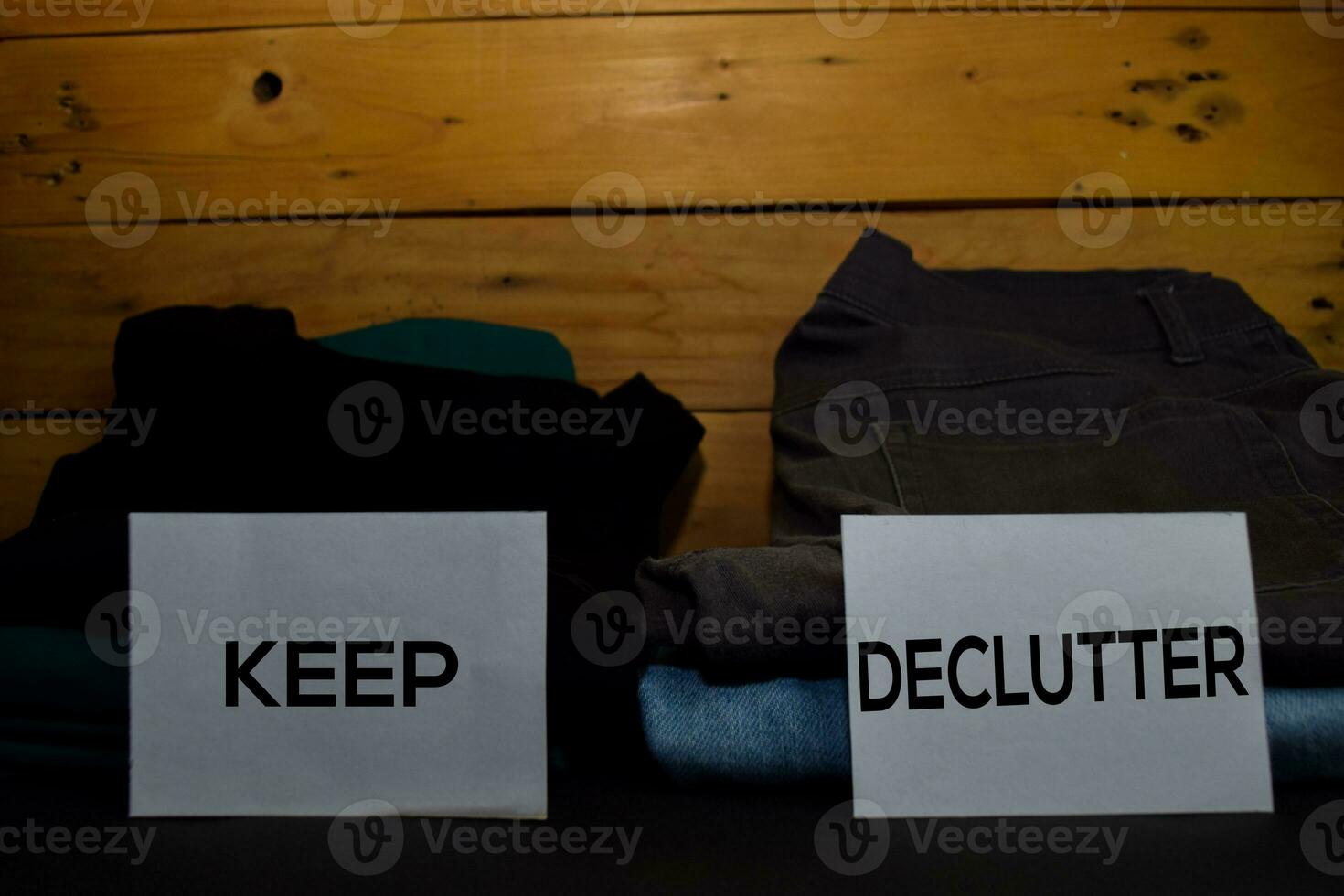 Keep and Declutter write on a sticky note between fashion clothes folded and stack isolated on wooden background. photo