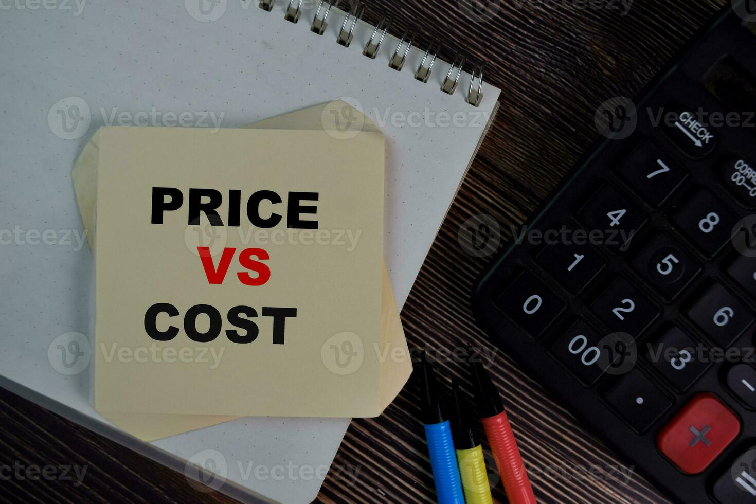 Price Vs Cost write on sticky notes isolated on Wooden Table. photo