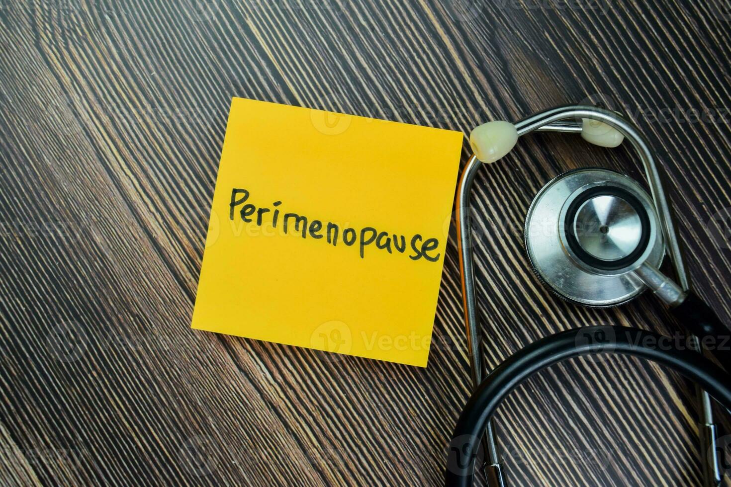 Concept of Perimenopause write on sticky notes with stethoscope isolated on Wooden Table. photo