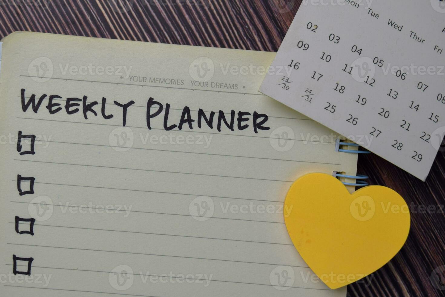 Weekly Planner write on a book. Supported by an additional services isolated on wooden table. photo