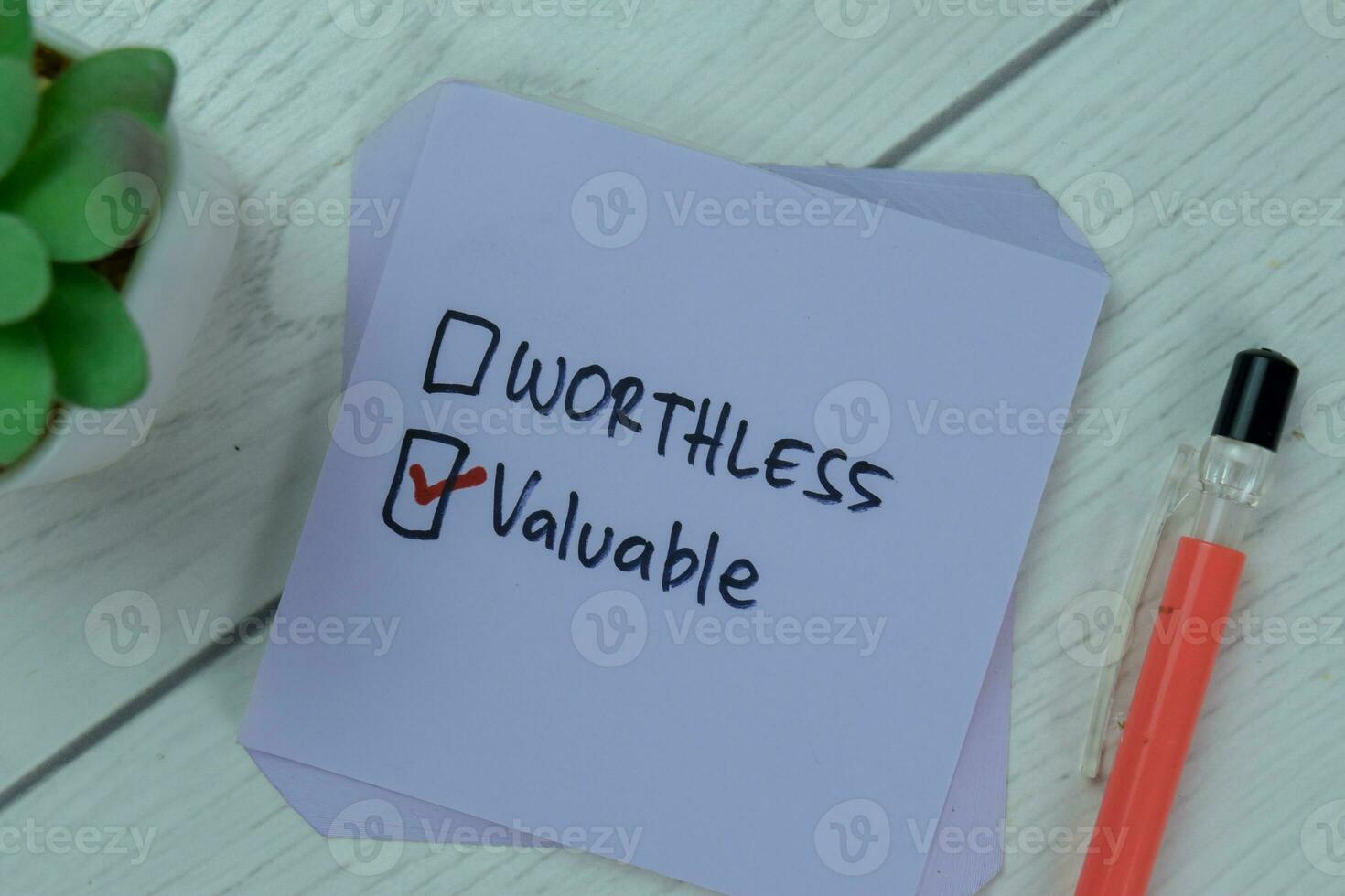 Concept of Worthless or Valuable Valuable write on sticky notes isolated on Wooden Table. photo