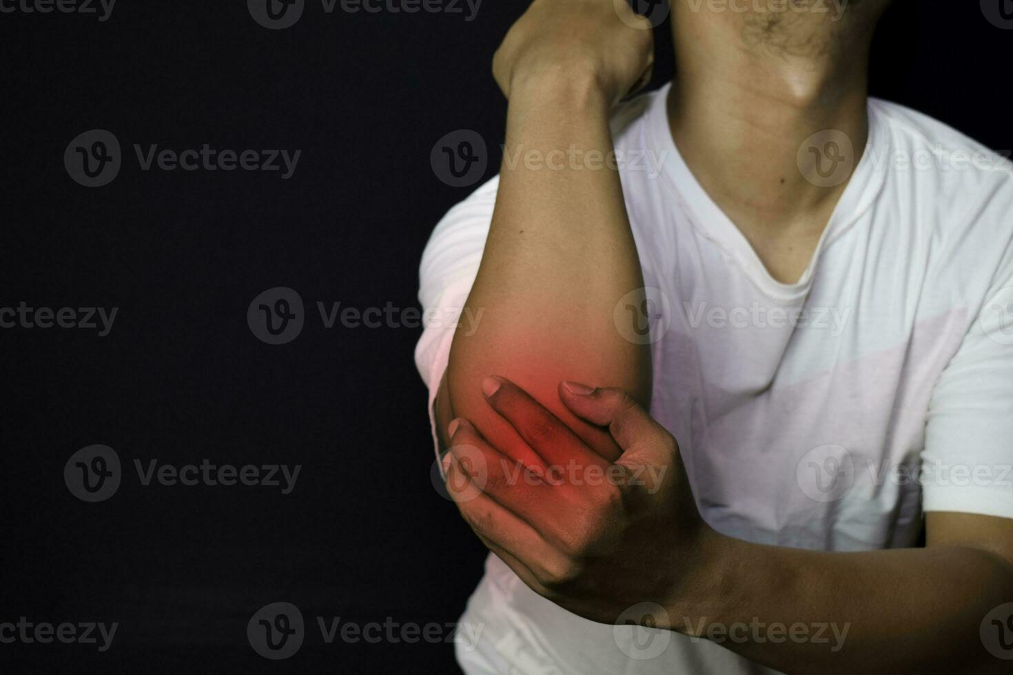 asiático hombre participación su mano. él siente dolor en su codo con negro antecedentes. médico o cuidado de la salud concepto foto