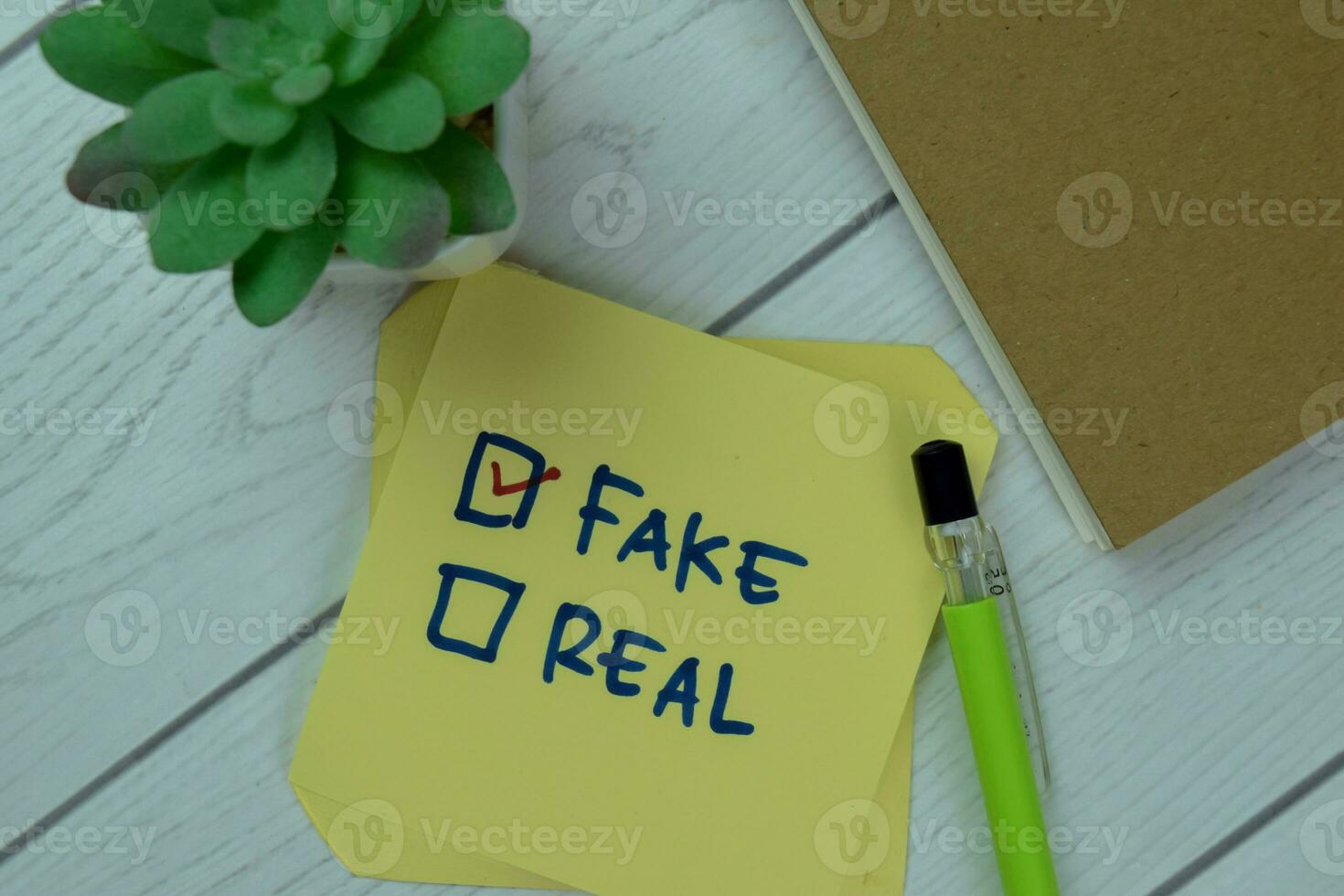 Concept of Fake or Real Fake write on sticky notes isolated on Wooden Table. photo