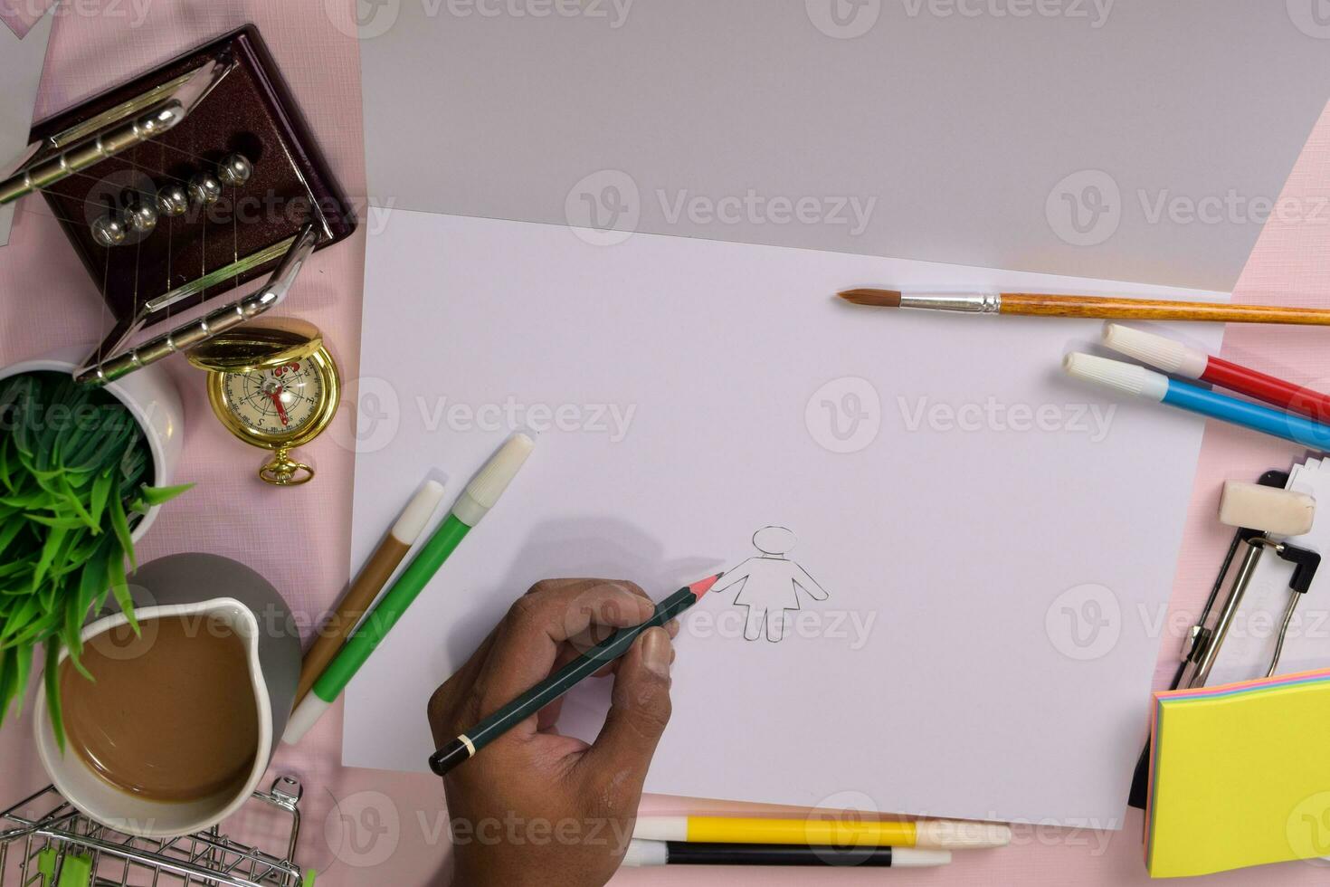 Top view of the man's hands drawing on a pink table, preparing to do homework in an open notebook with a marker in hand. Drawing Working Desk Concept. photo
