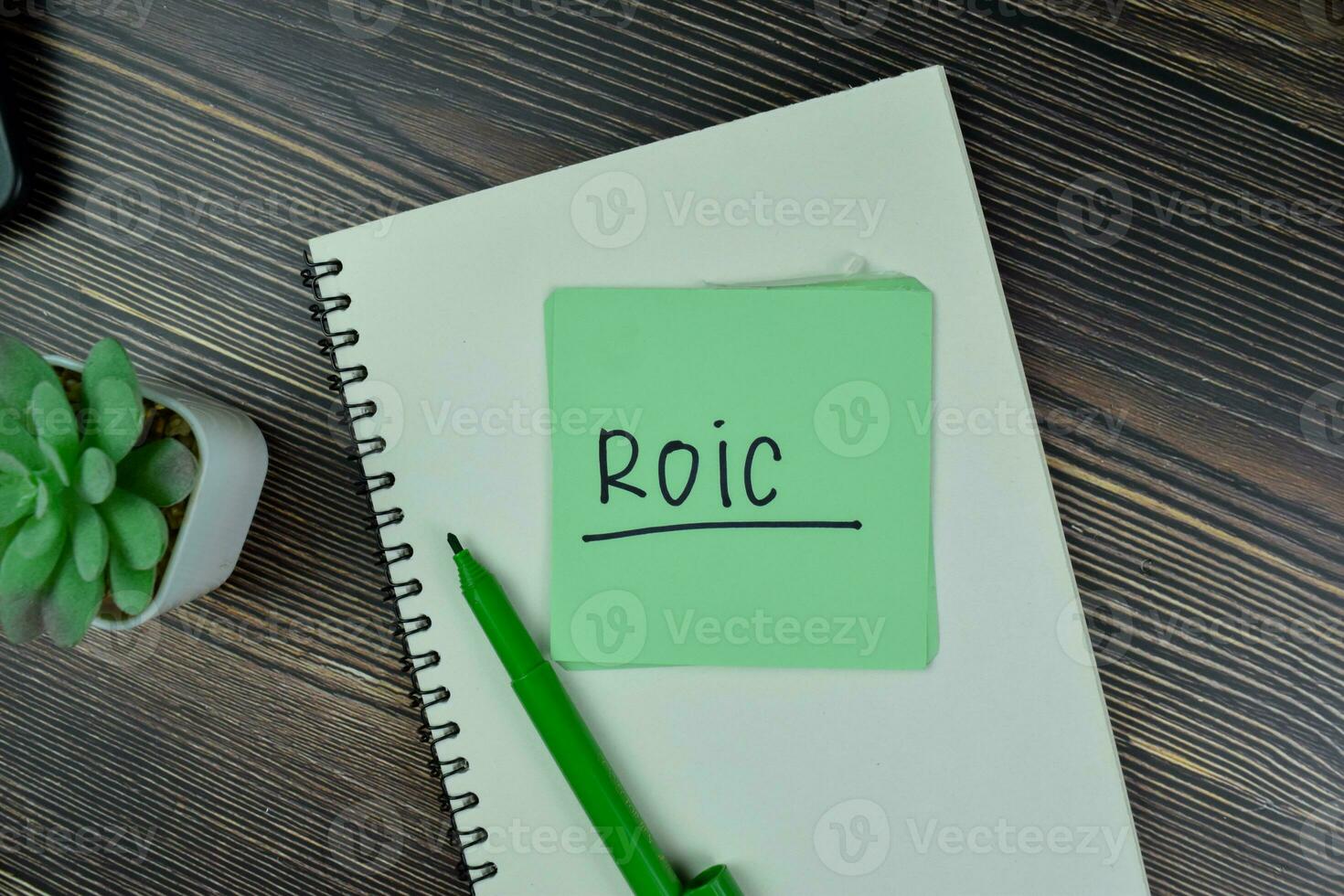 ROIC - Return on Invested Capital write on sticky notes isolated on Wooden Table. photo