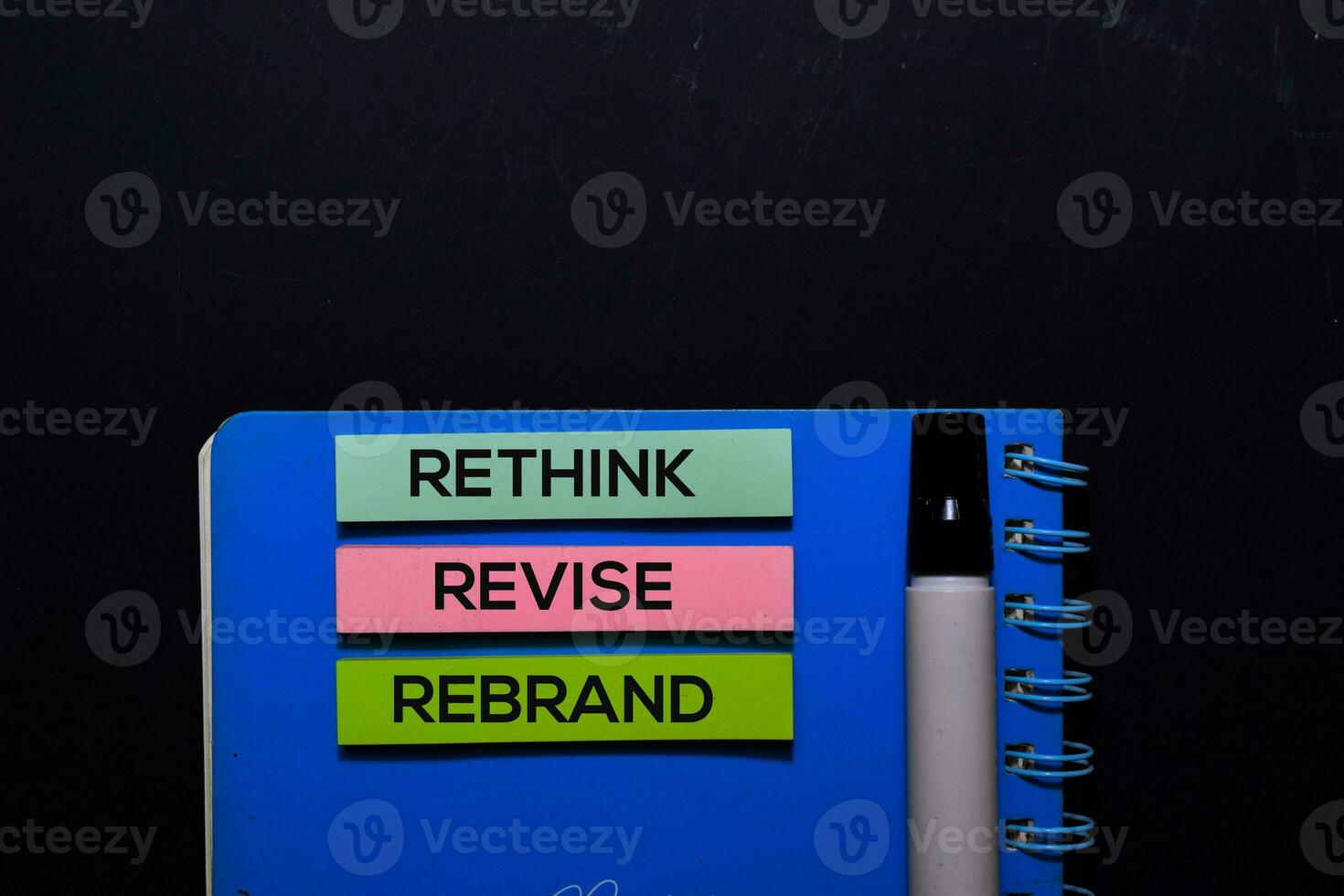 Rethink Revise Rebrand write on Sticky Notes. Top view isolated on black background. photo