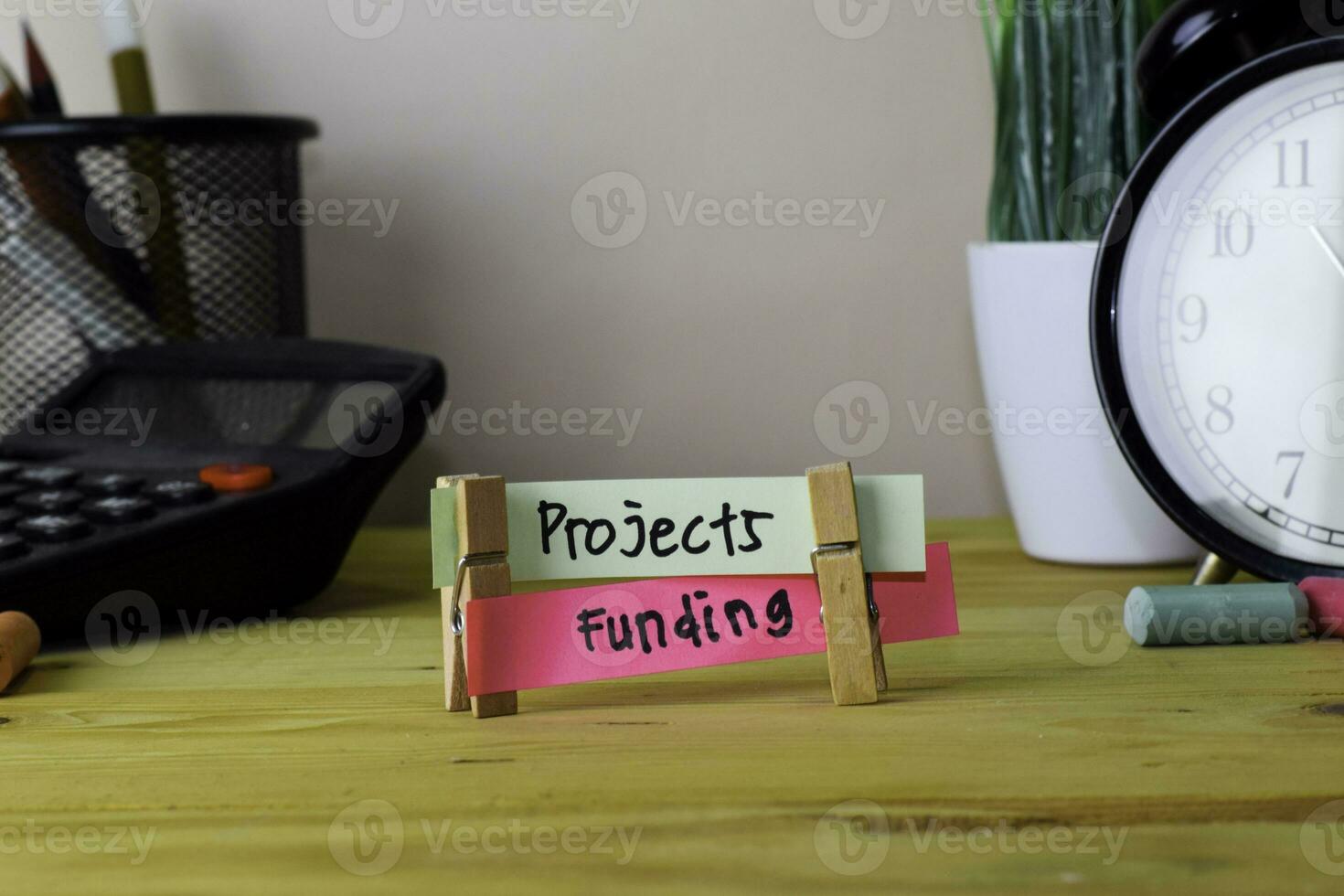 Projects and Funding. Handwriting on sticky notes in clothes pegs on wooden office desk photo