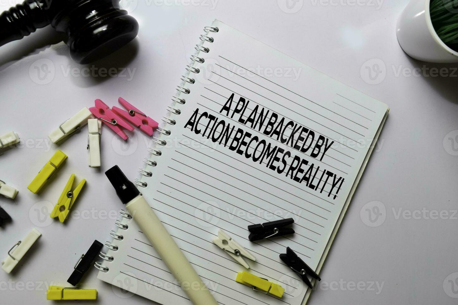 A Plan Backed By Action Becomes Reality text on a book at office desk. Motivation concept photo