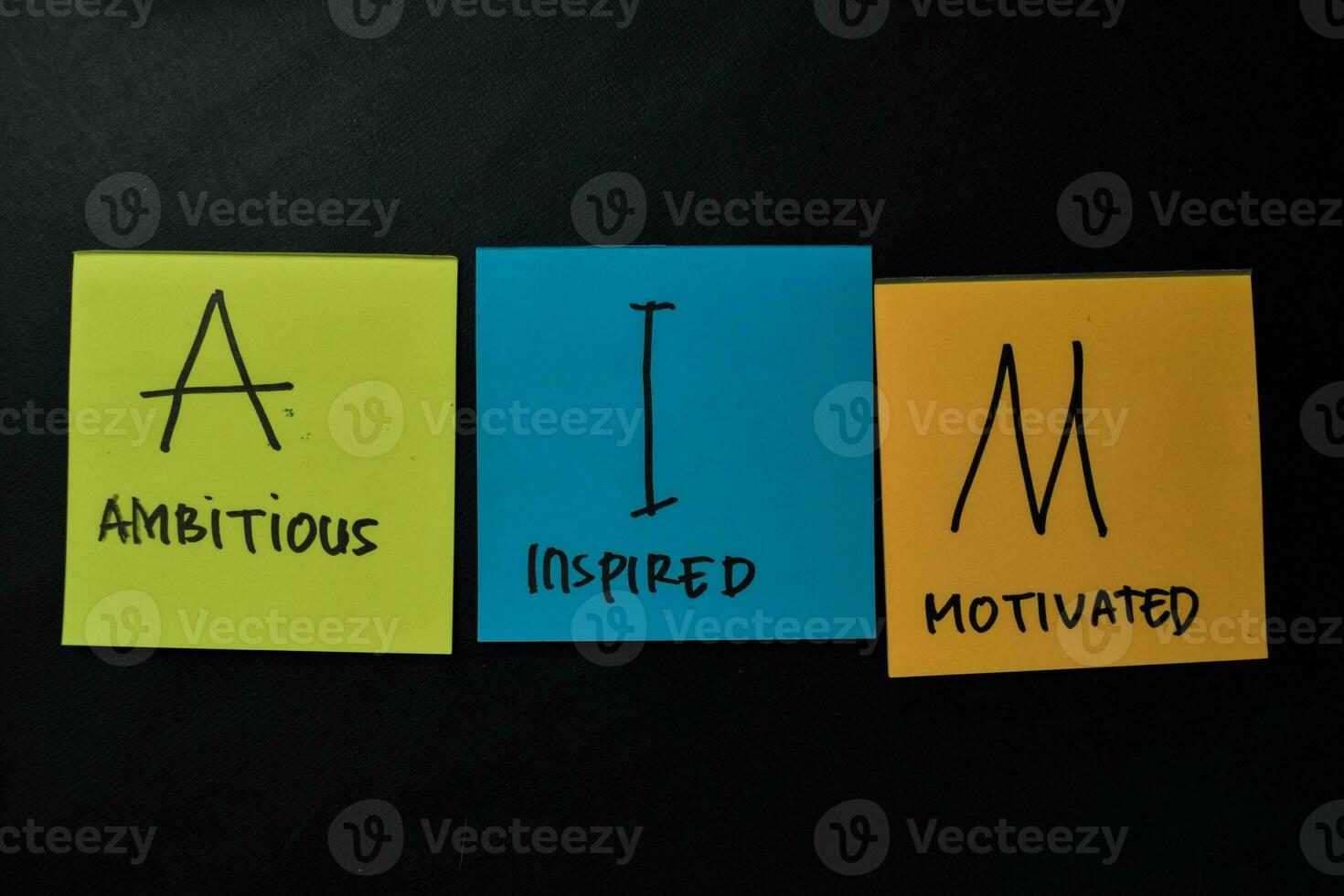 AIM - Ambitious Inspired Motivated write on sticky notes isolated on office desk. photo
