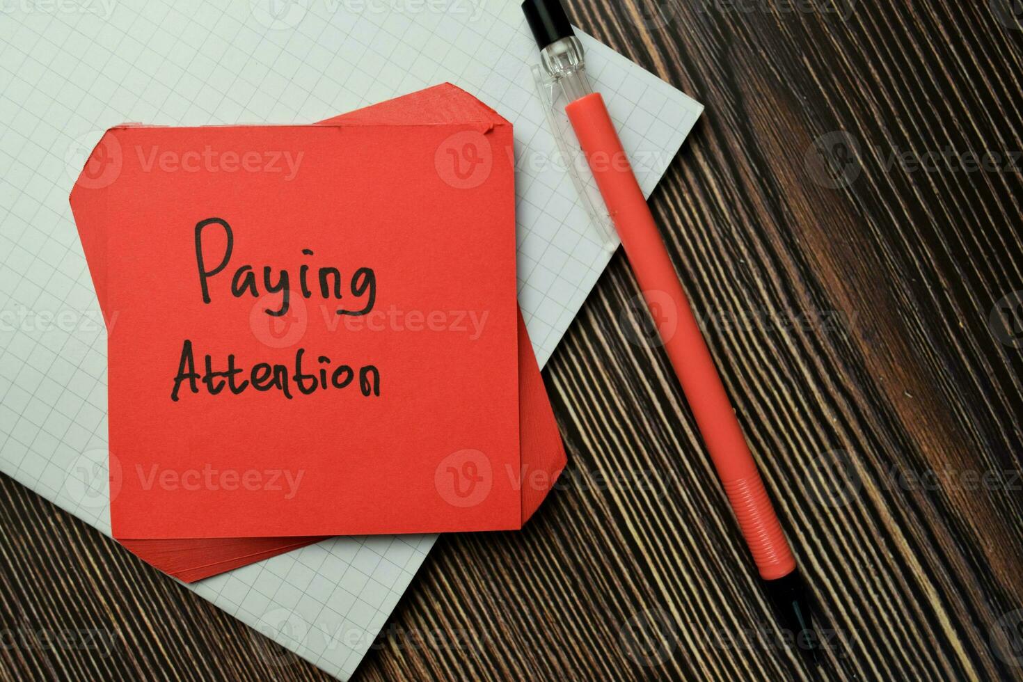 Paying Attention write on sticky note isolated on Wooden Table. Financial Concept photo