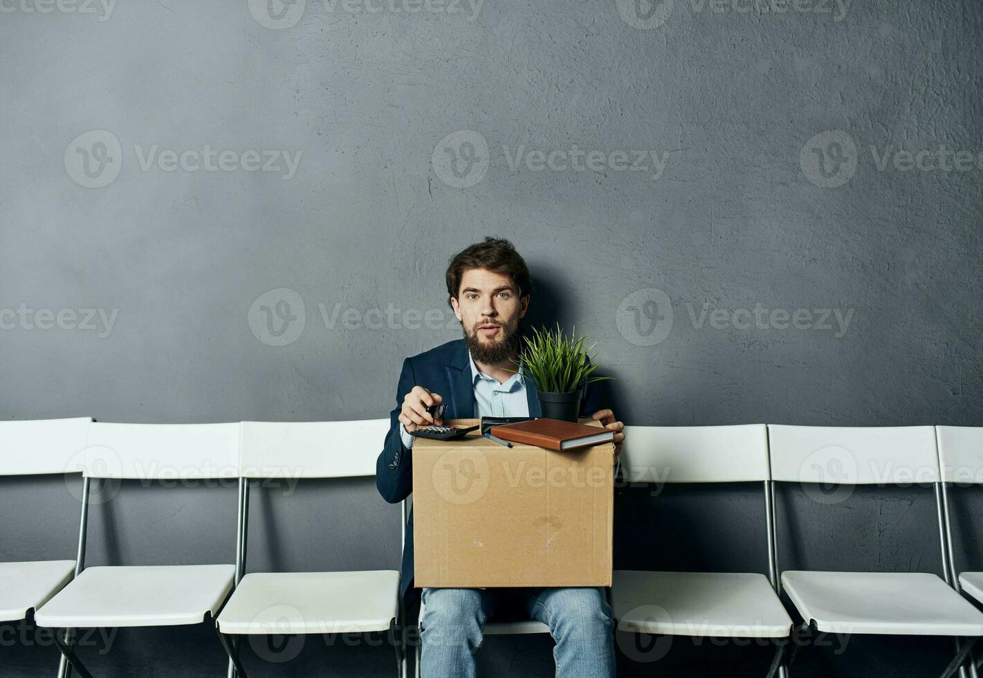 A man with things in a box sits on a chair waiting for discontent photo