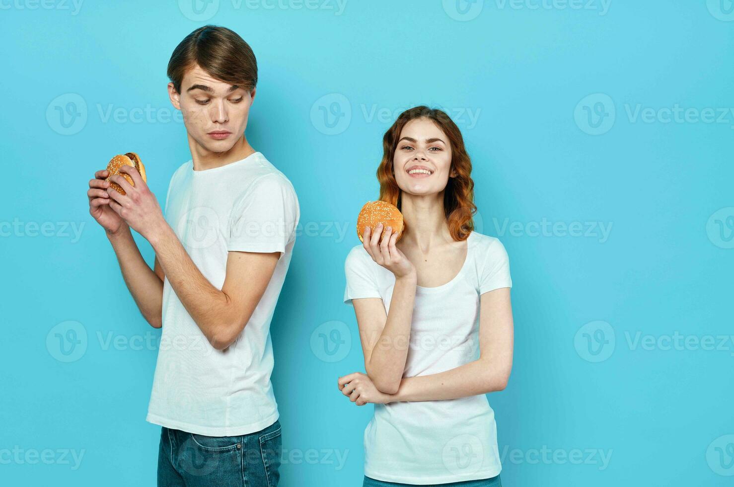 cheerful young couple in white t-shirts having fun fast food hamburgers photo