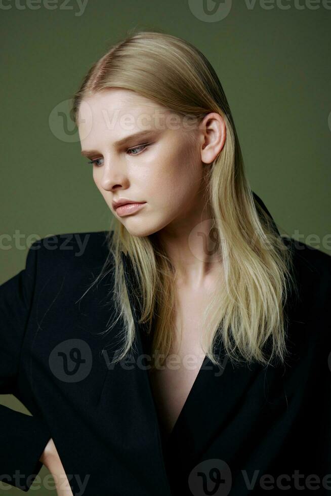 A self-confident young woman looks away posing in the studio on a green background photo