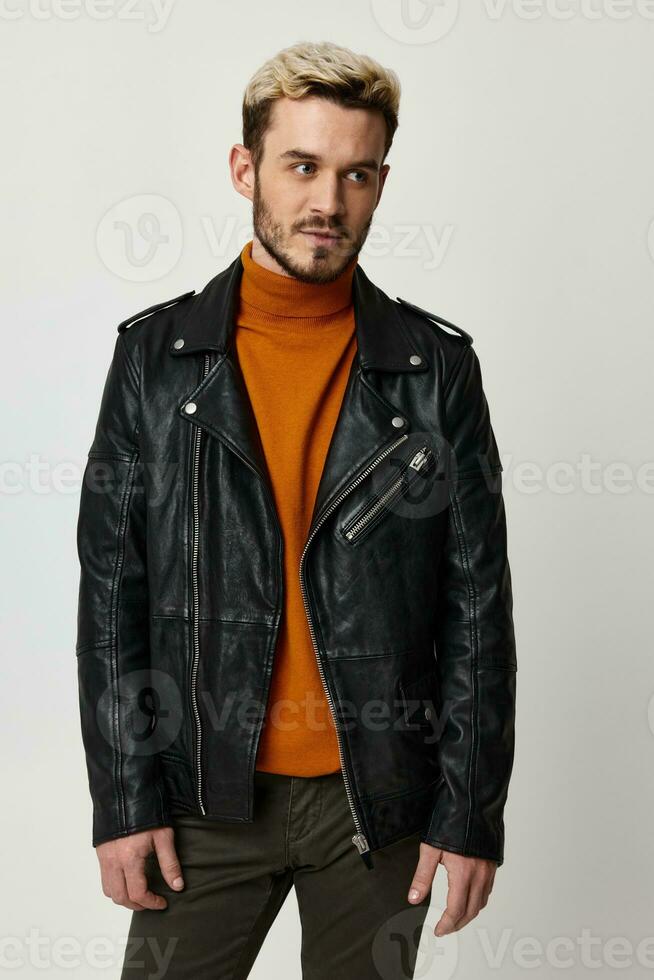 blond man in orange sweater and leather jacket on light background cropped view photo