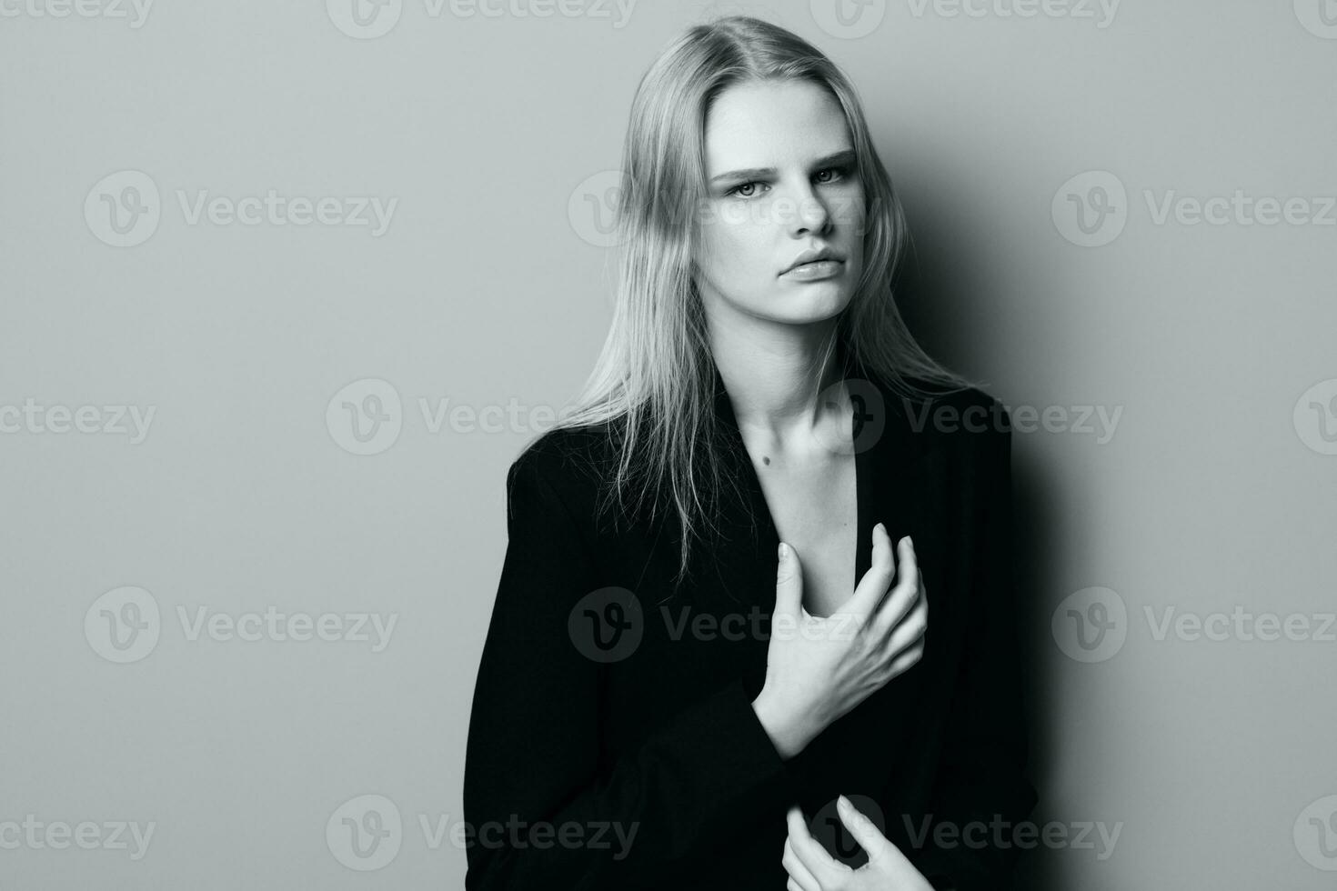 Sexy expressive professional model touching her jacket and looks at camera. Beautiful blonde lady posing at studio. Good offer for fashion brands. Minimalistic art style photo