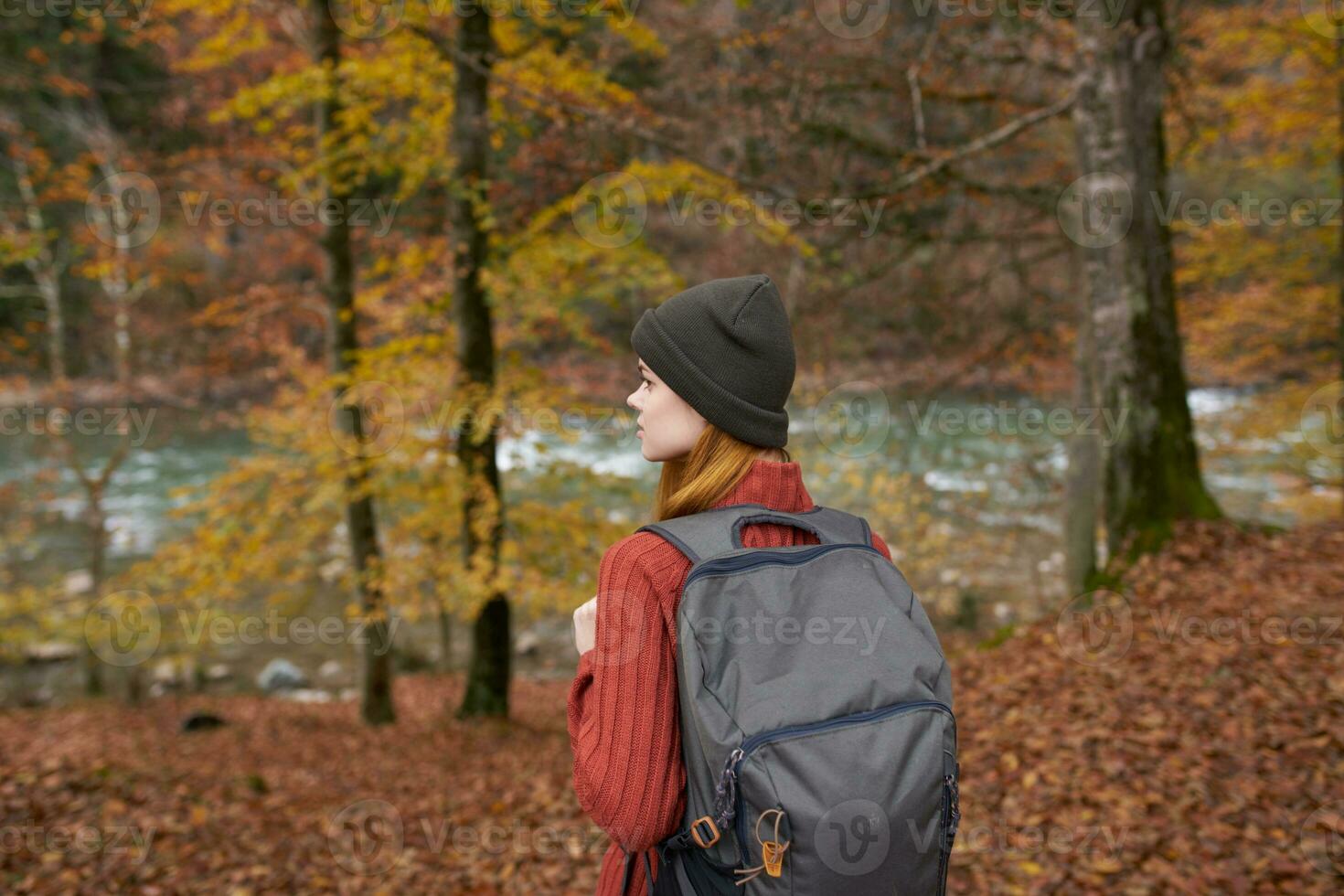 traveler with a backpack and in a gray hat in the autumn forest fallen leaves trees river model photo