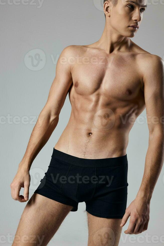 sporty man in black shorts on nude body gray background muscle photo