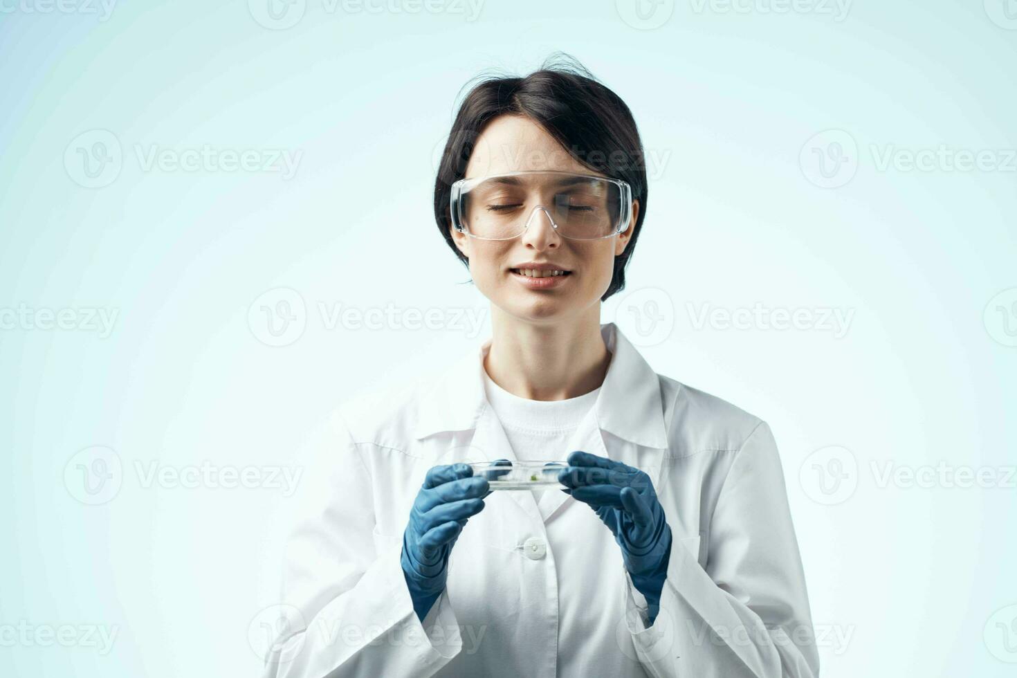 female laboratory assistant looks through a magnifying glass at a biochemical research process photo