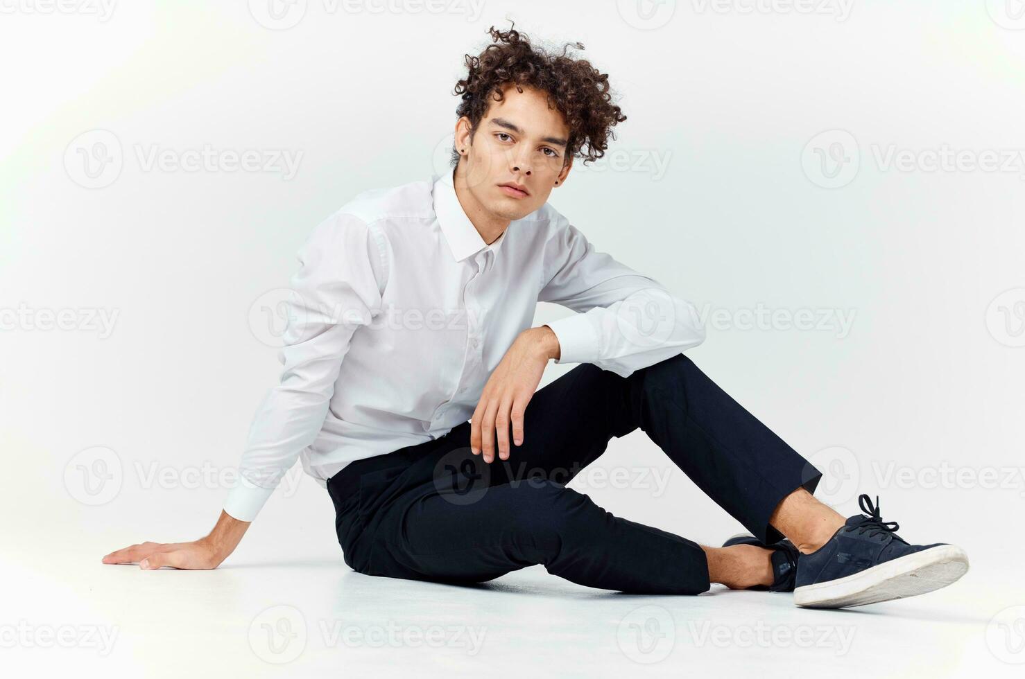 teenager in sneakers, black trousers and a white shirt In a bright room in full growth photo