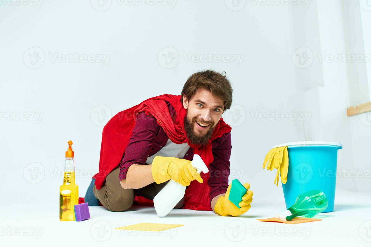 A man with cleaning supplies in a red raincoat on the floor of a home interior professional photo