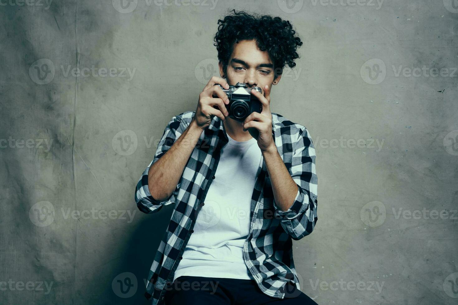 guy with a camera in his hands on a gray background indoors hobby plaid shirt model photo