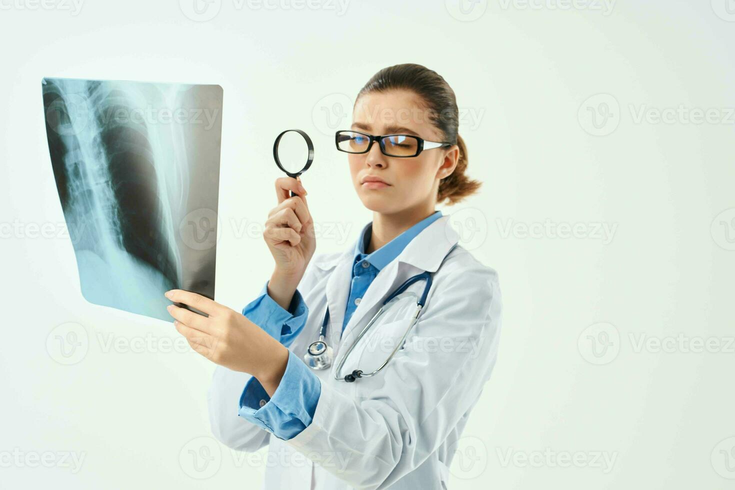 a nurse in a white coat looks through a magnifying glass at an x-ray photo