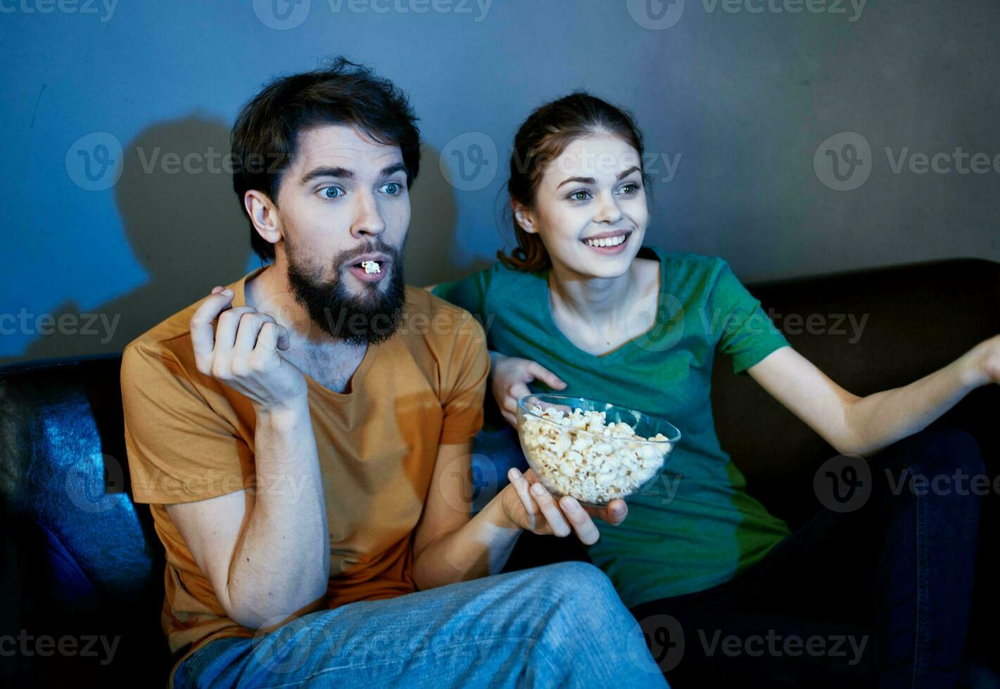 amigos hombre y mujer acecho televisión en el sofá y palomitas de maiz en un plato foto