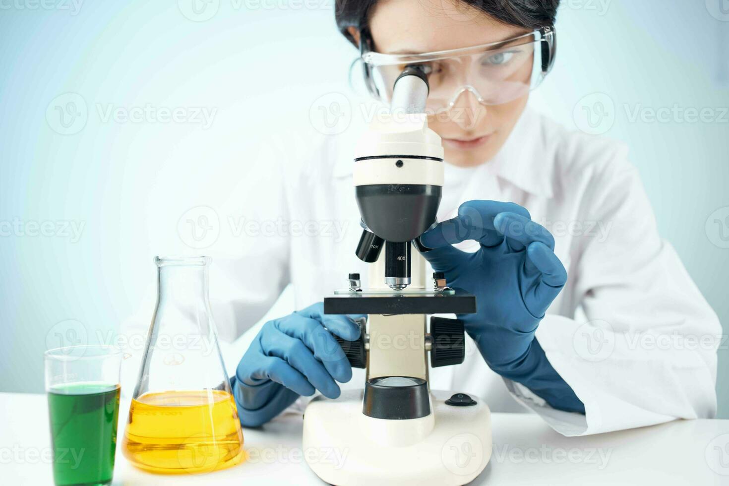 mujer mirando mediante un microscopio químico solución laboratorio investigación biotecnología foto