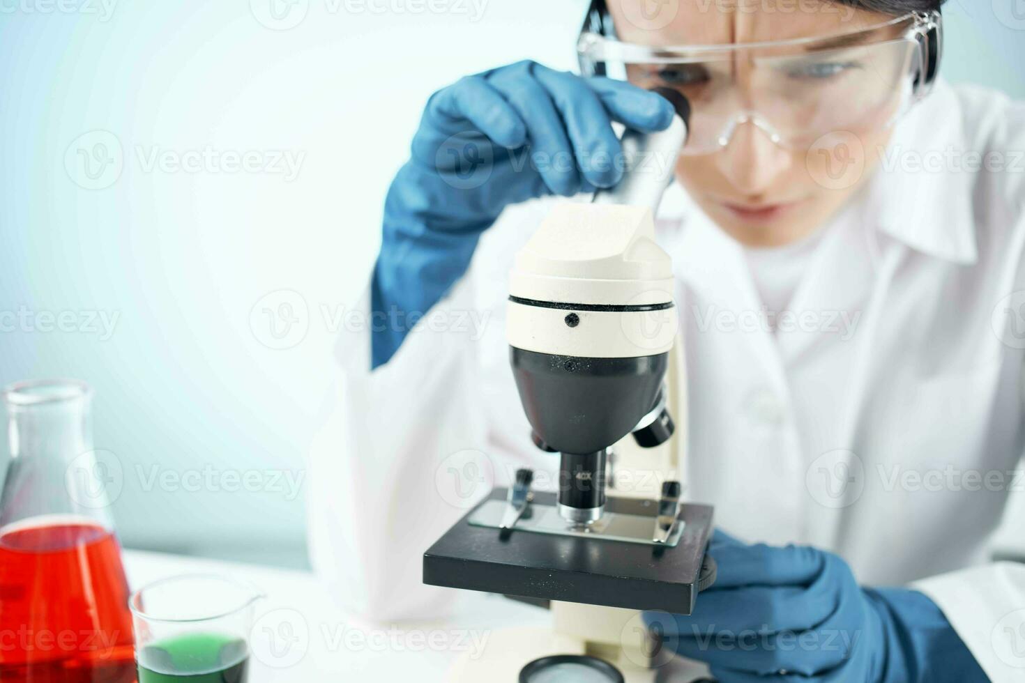 Woman in white coat looking through microscope research technology experiment photo