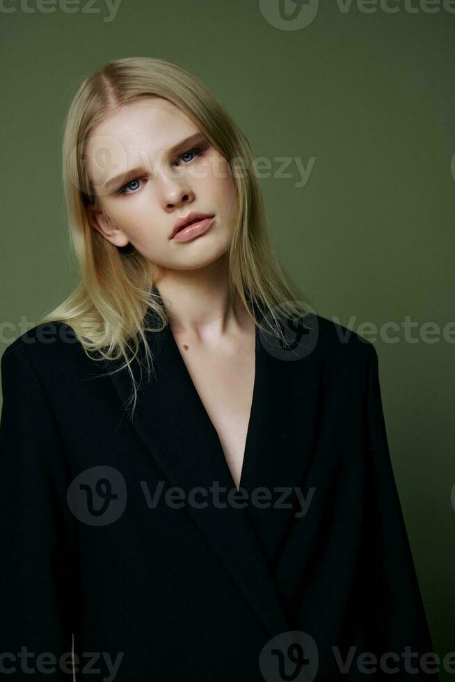 Portrait of a stunning elegant girl in a black suit posing professionally on a green background in the studio. The concept of advertising for designer brands photo