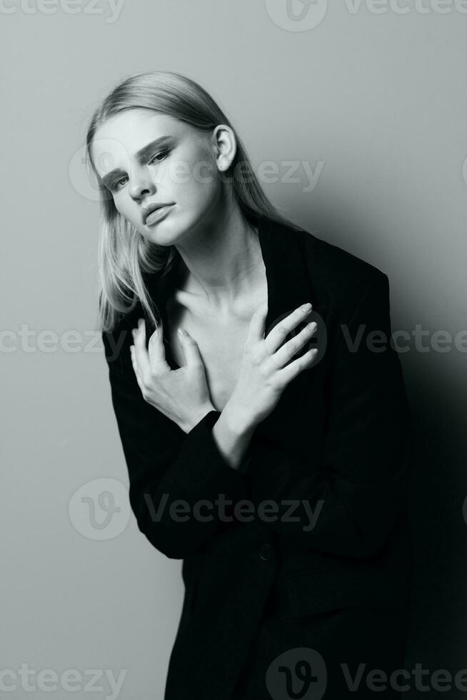 Blonde in a suit hugs herself while putting on a jacket photo