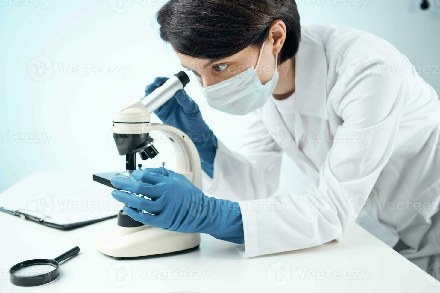 laboratory assistant wearing a medical mask looking through a microscope Professional research experiment photo