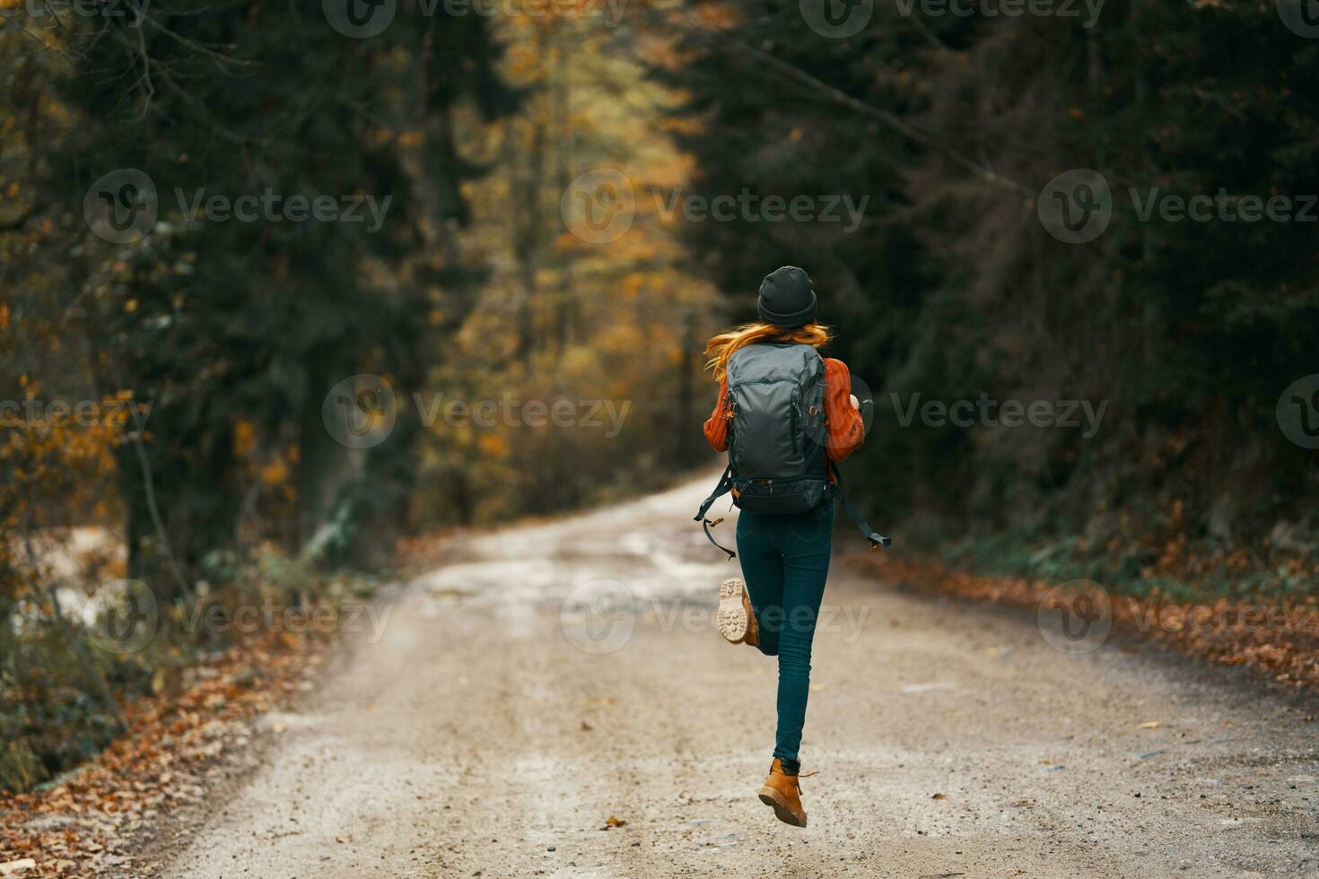 happy traveler with backpack walks on the road in autumn forest photo