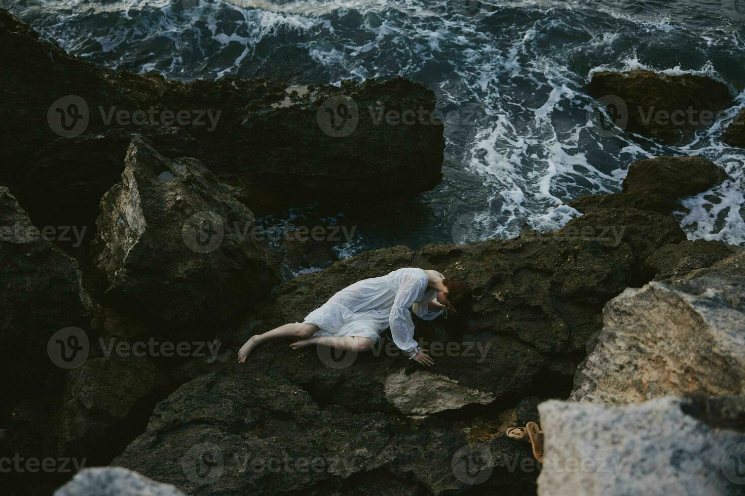 beautiful young woman in a white dress lying on a stone in a white dress landscape photo