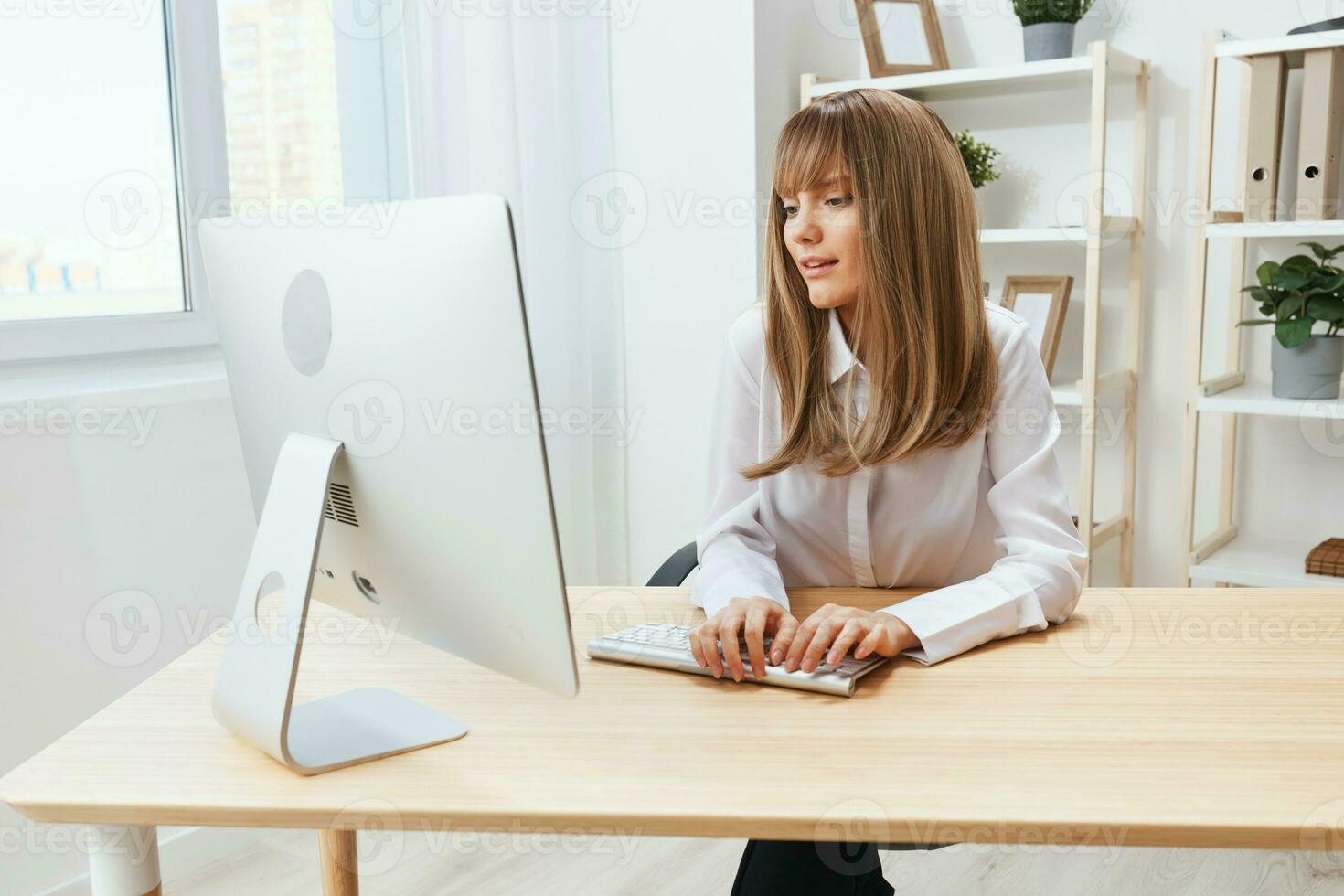 Happy smiling adorable blonde businesswoman worker freelancer look at screen typing answer for clients in light modern office. Cheerful employee work on computer online in support service. Copy space photo