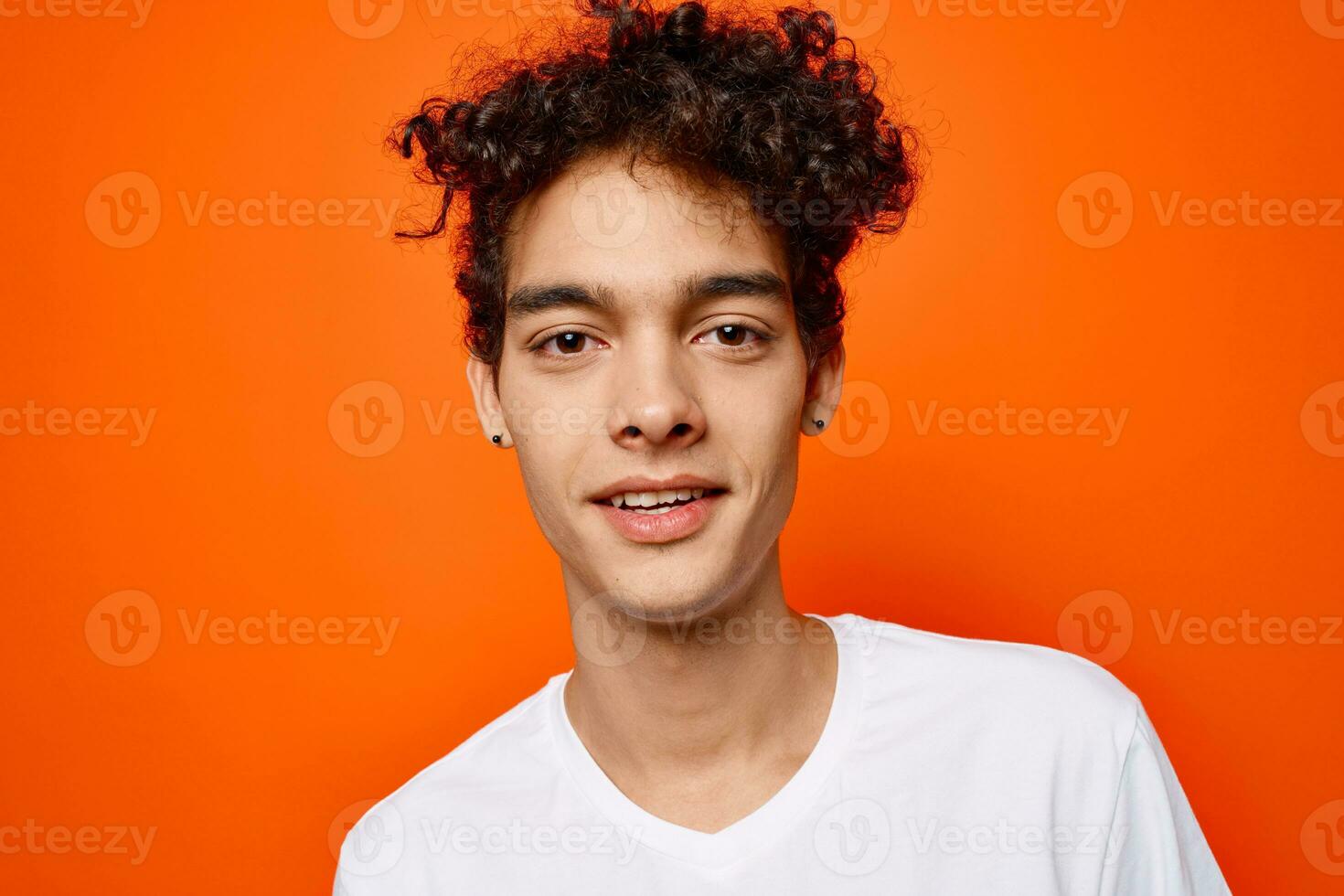 cute guy curly hair emotions grimace studio orange background photo