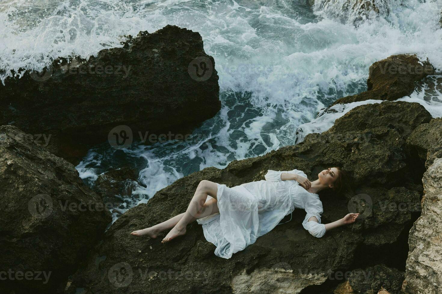 Beautiful bride lying on rocky coast with cracks on rocky surface unaltered photo