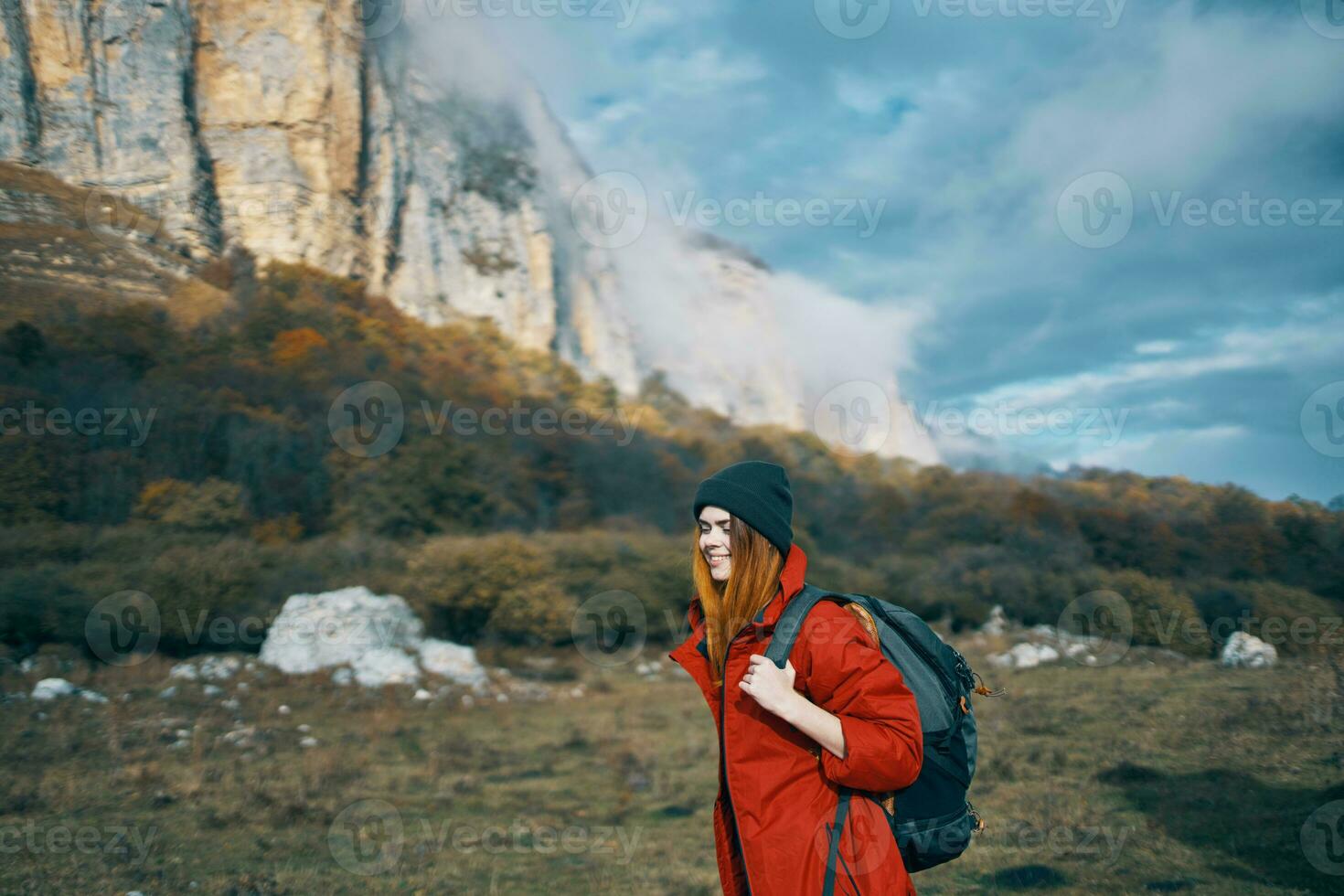 travel of a woman in a jacket with a backpack hat on his head blue sky and high mountains photo